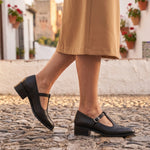 Susana: zapatos tira en t brogue, color negro, puestos en los pies sobre empedrado de Granada